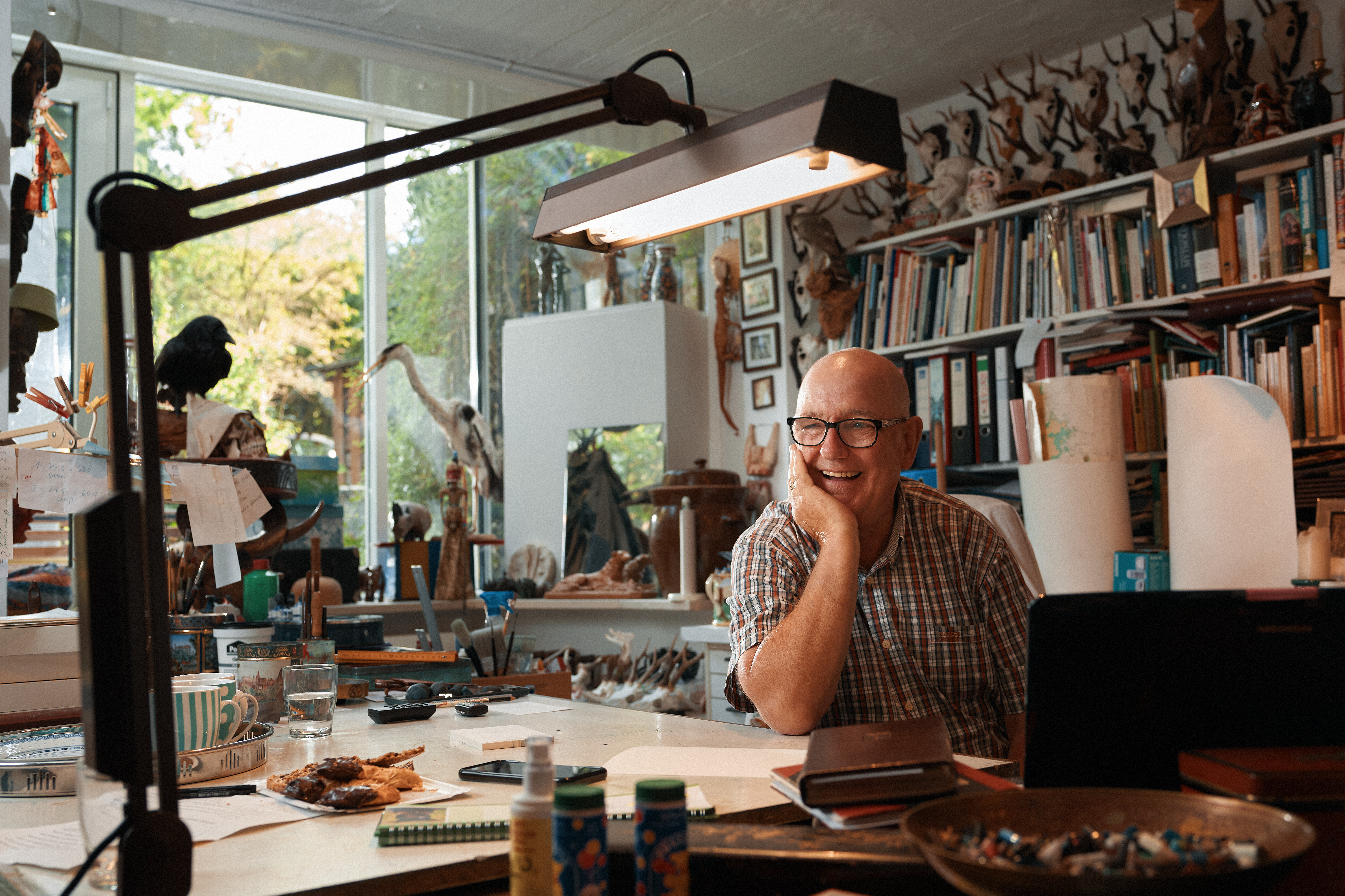 Der Künstler Hans Ruprecht Leiß lacht in seinem Atelier in die Kamera.