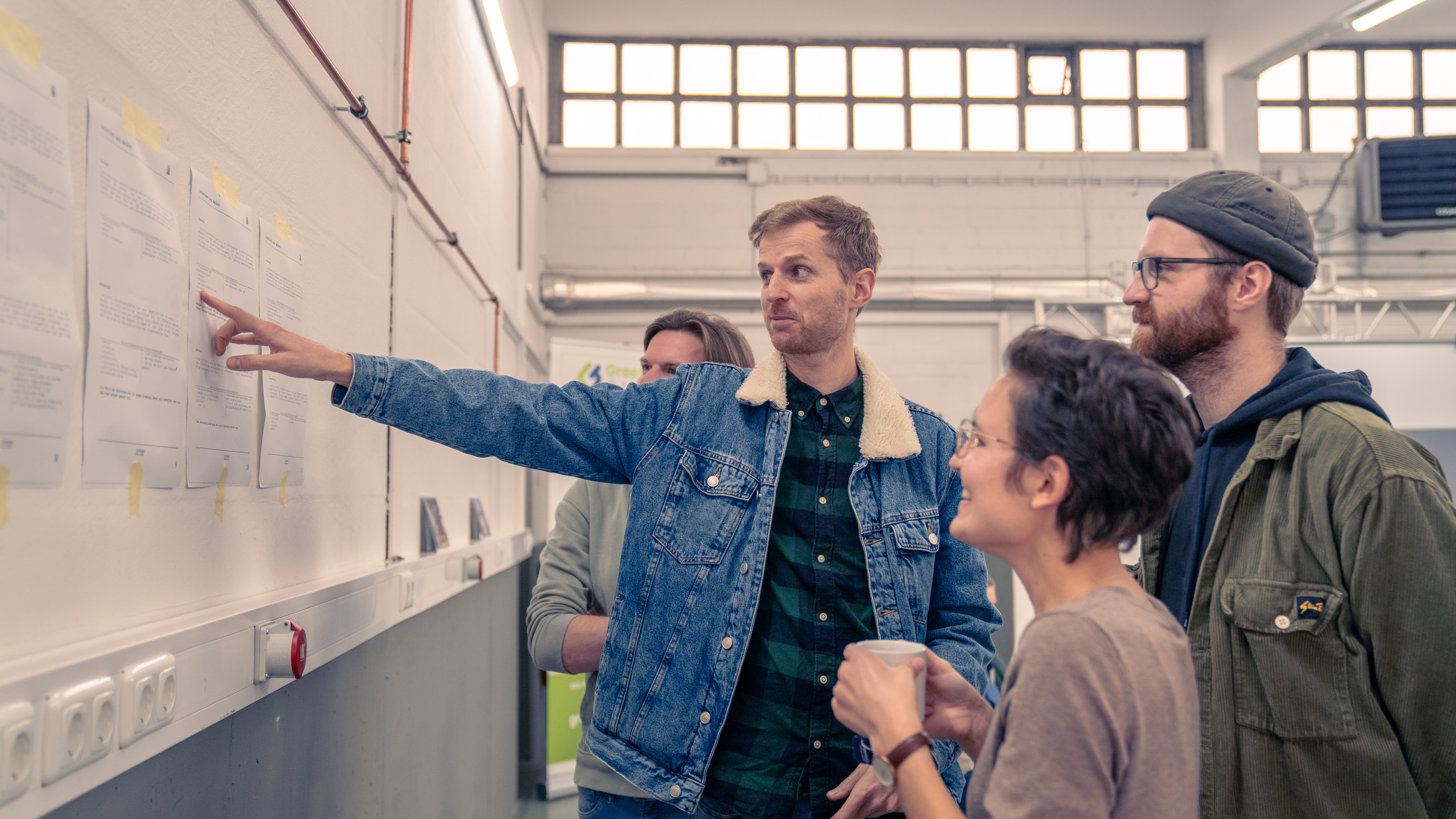 Mehrere Personen aus dem Team von visuellverstehen besprechen etwas vor einer Reihe von an die Wand geklebten Zetteln.